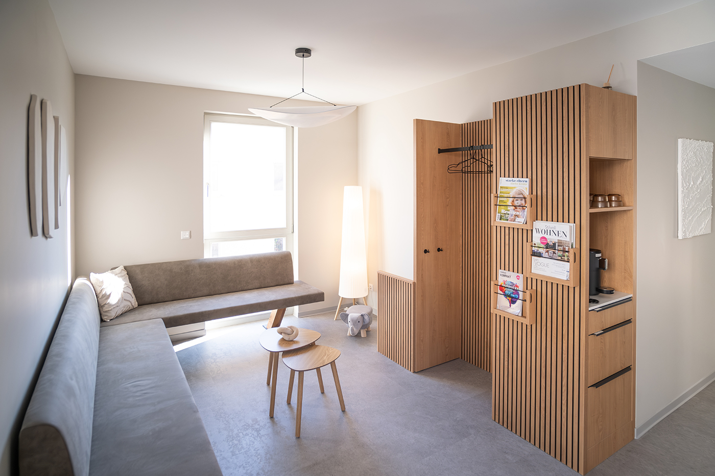 Wartezimmer der ELBIMPLANT Zahnarztpraxis & Oralchirurgie mit gemütlicher Couch, Garderobe, Tisch usw.
